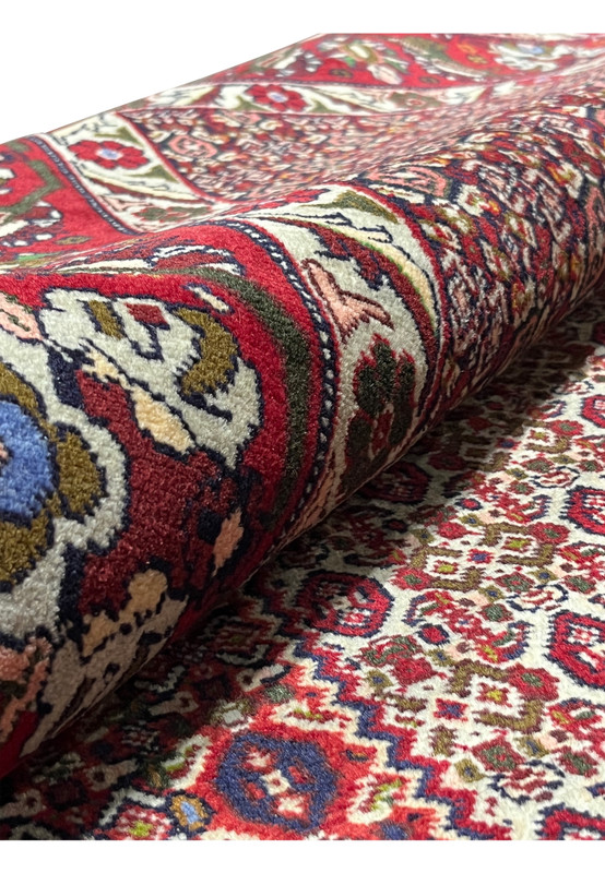 Rolled view of Persian Senneh rug showing flexibility, dense wool pile, compact structure, and balanced geometric surface patterning