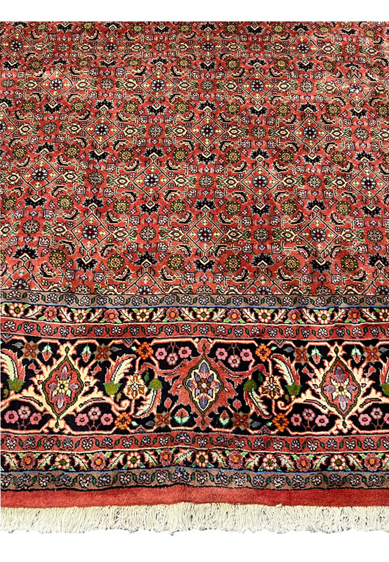 Lower border detail of Persian Bijar rug featuring floral vines, palmettes, and rich navy blue ground