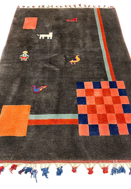 Top view of Persian Gabbeh rug with scattered animal and human figures, open charcoal field, and bold geometric color blocks