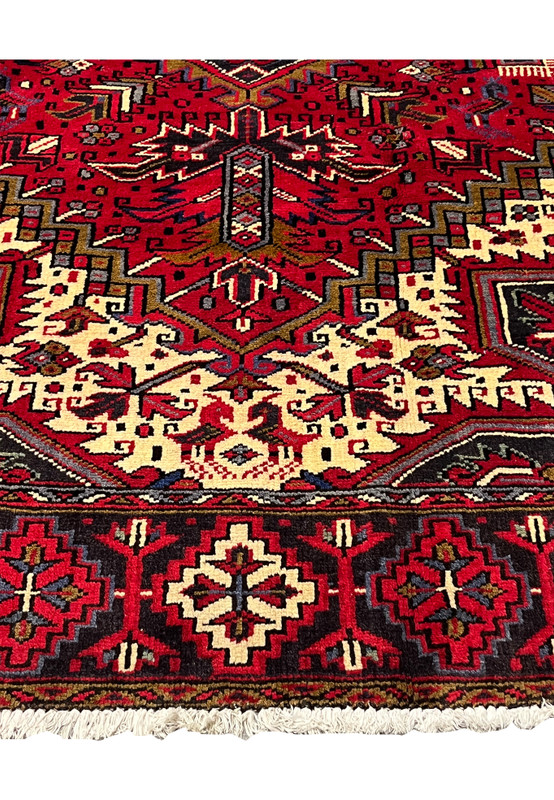 Lower border view of Persian Heriz rug with repeating geometric rosettes strong guard stripes and structured tribal framing