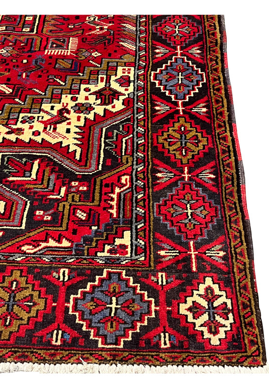 Border closeup of Heriz tribal rug displaying repeating diamond motifs stylized flowers and classic village weaving details