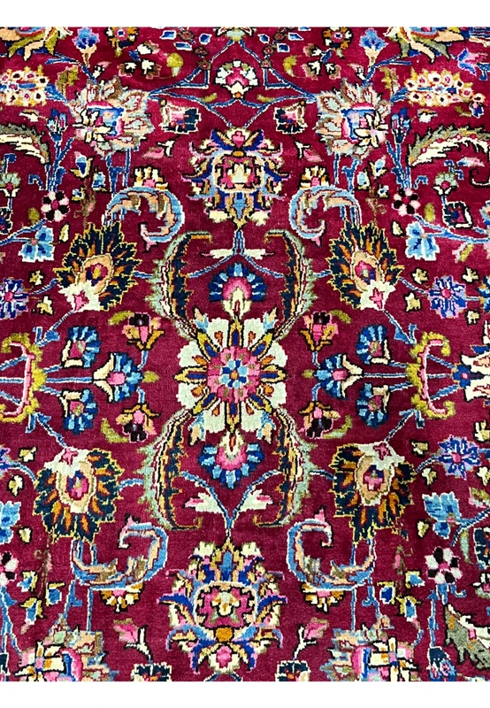 Closeup of central medallion with floral rosettes, navy outlines, and multicolor highlights woven in fine wool.