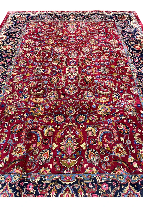 Top down view of signed Mashad rug highlighting symmetrical floral layout, central medallion, and detailed vine motifs