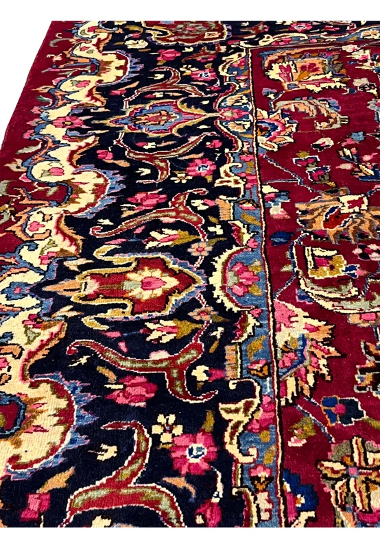 Zoomed border detail of Persian Mashad rug with dark navy ground, ivory floral motifs, layered guard borders, and crisp hand knotted lines.