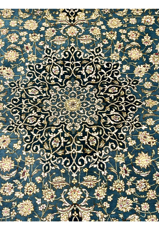 Central medallion close up with navy and ivory arabesques and floral silk detailing on deep teal field