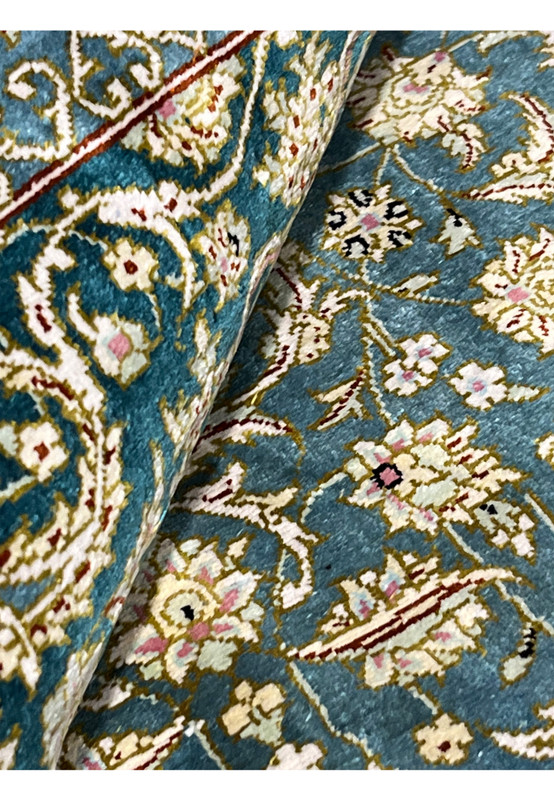 Rolled corner view of Persian Qum silk rug demonstrating flexibility, thin high density weave and luxurious silk structure