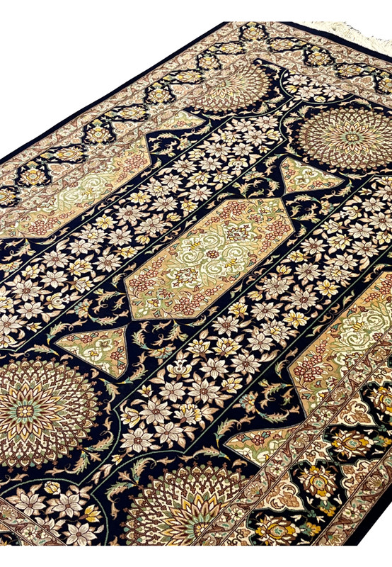 Angled studio shot showing sheen of silk surface dense knotting floral panels and medallions authentic signed Persian Qum collector rug.