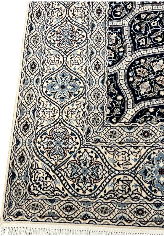Side view showing low dense pile of Persian Nain 6 LA Kork wool rug with silk floral highlights navy dome pattern.