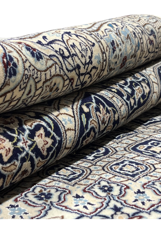 Rolled 6'9 x 10 Persian Nain Habibian 6 LA Kork and silk rug showing ivory field navy Gombadi dome pattern and tight pile.