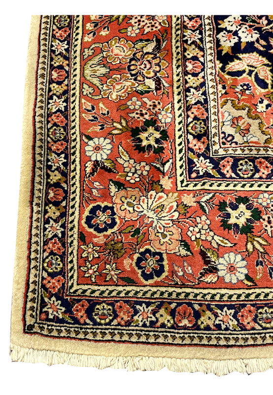 Coral red border detail of Persian Bijar rug with repeating floral clusters navy outlines and ivory guard bands
