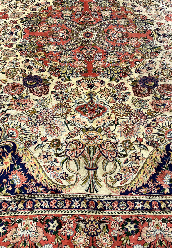 Detailed floral motifs on Persian Bijar rug with coral medallion ivory ground navy accents and intricate vine work