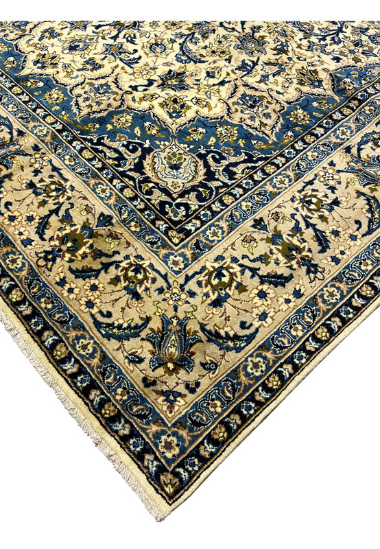 Edge detail of handmade Persian Kashan rug showing navy guard borders ivory field tight wool pile and finished fringe