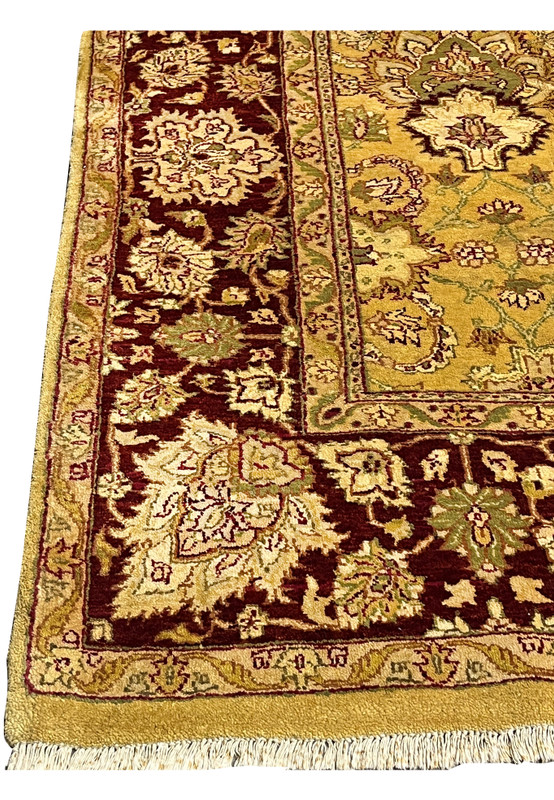 Rich burgundy main border detail with large ivory floral blossoms and olive vine work framing the gold field Agra rug.