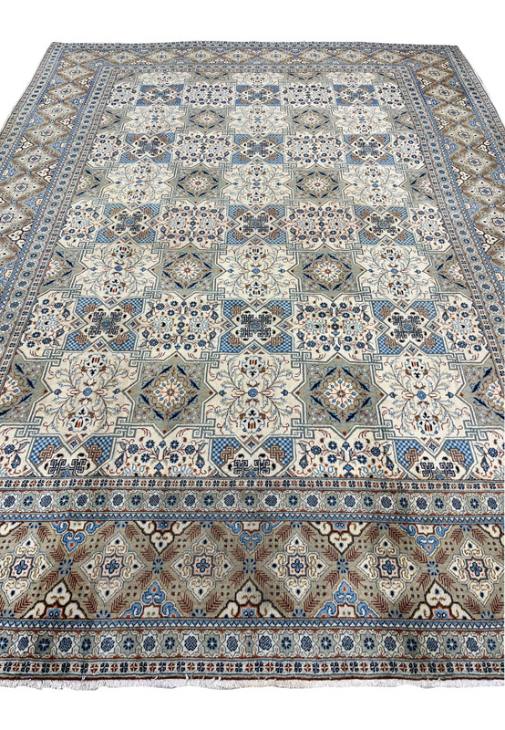 Close-up detail of the central field of a Persian Tabriz rug, revealing the intricate floral bouquets inside ivory star medallions, blue-and-white checkerboard diamond interstices, and angular Greek-key motifs connecting the compartments.