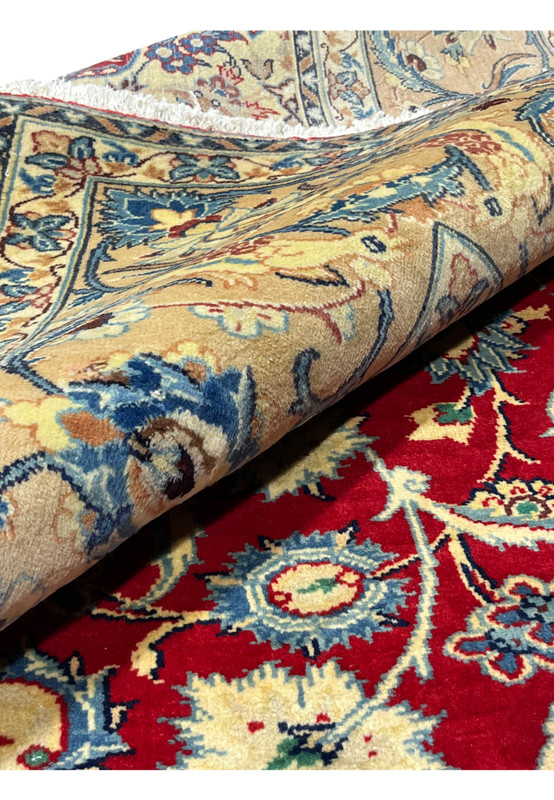 Rolled 10x13 Persian Isfahan wool rug showing pile depth ivory border floral arabesques crimson red field handmade