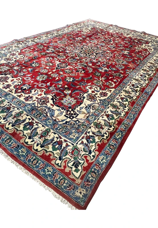 Angled view 8x12 handmade Persian Isfahan wool rug crimson red field ivory border blue green floral medallion