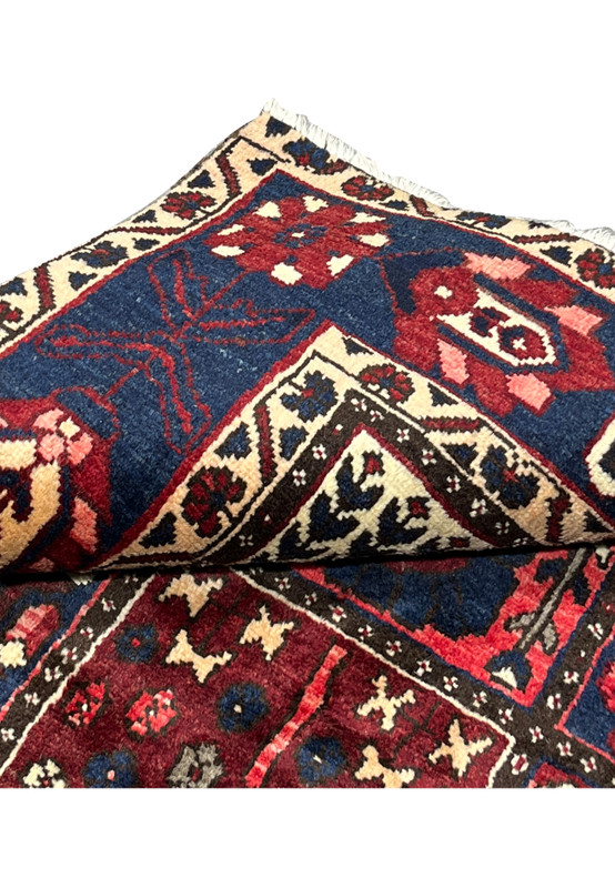 Folded corner of 7x10 hand-knotted Bakhtiari Persian rug revealing weave structure and pile height