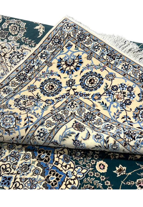 Folded edge revealing the flexibility and tight hand-knotted construction of this 600 KPSI Nain rug