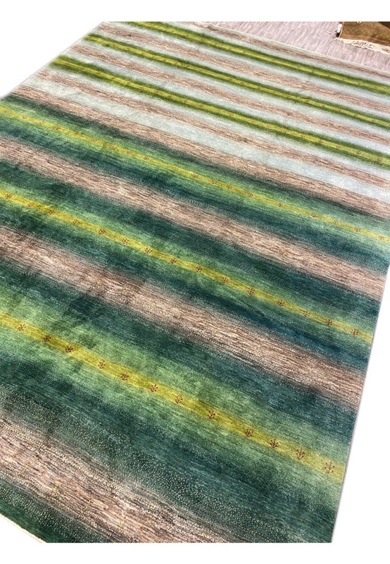 Modern designer Indo Gabbeh oversize rug angled view in lush green sage and natural earth tones