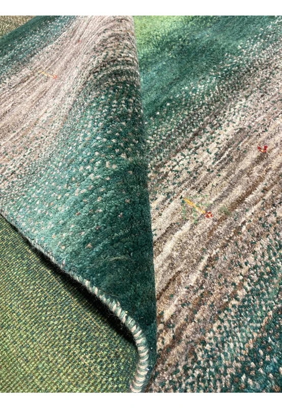Emerald and teal striped Gabbeh wool pile shown rolled, revealing dense hand-knotted construction