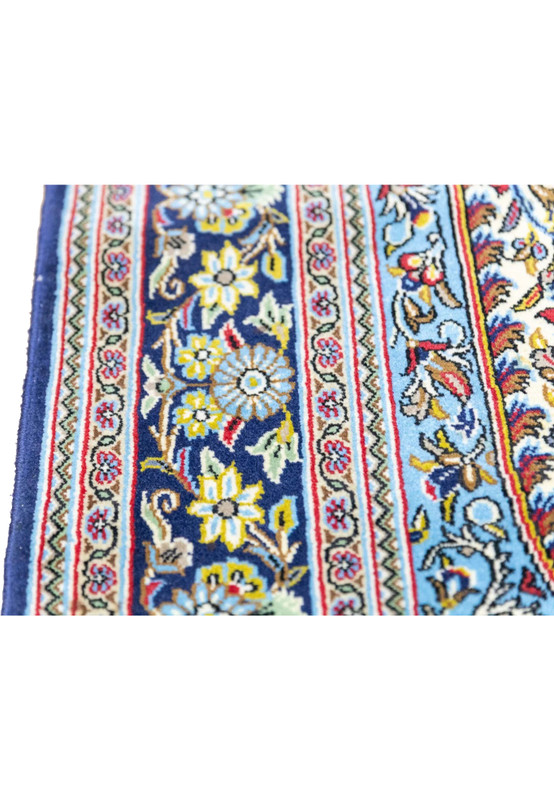 Close-up of indigo main border with sky blue lotus rosettes and pale lavender guard stripes on Qum rug