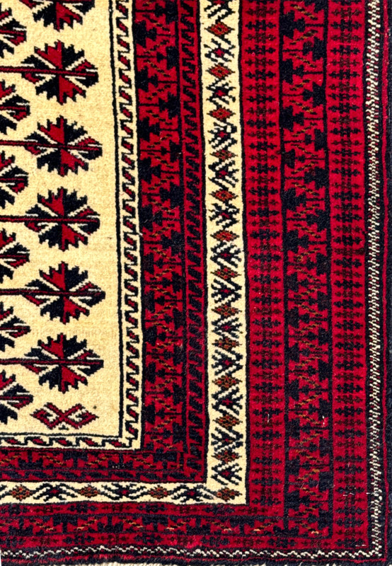 Crimson red main border close-up of Persian Baluch tribal rug with ivory zigzag guard stripes