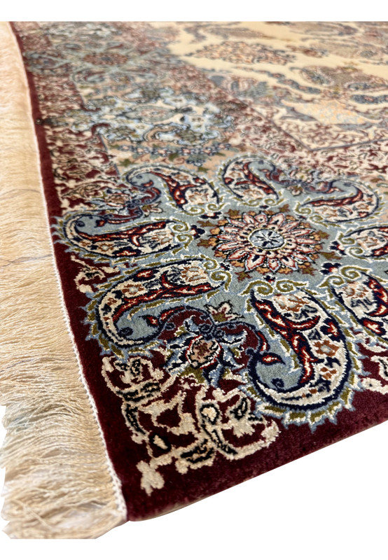 Edge detail of fine hand-knotted Isfahan rug showing ivory fringe and silk-highlighted border patterns