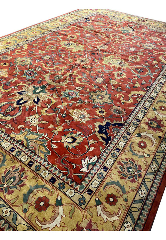 Angled view of oversized Indo Agra mansion rug with luminous gold main border framing the red field