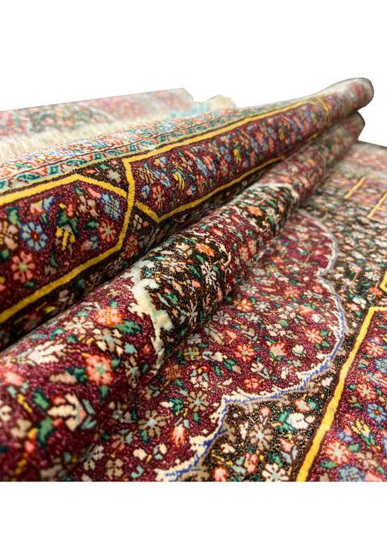 Rolled view of the Qum showing the supple drape and luxurious silk pile of this rug