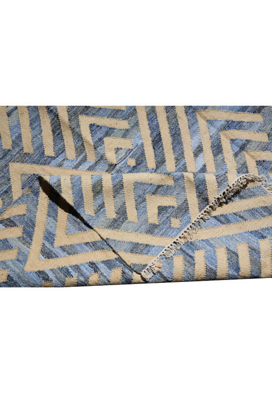 Folded corner of the blue and cream flatweave revealing the reverse side and the tight cotton weave structure