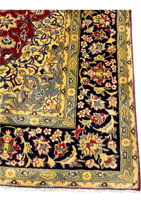 Close-up of the navy main border populated with palmettes lotus blossoms and the slow curl of classical Persian vine scroll