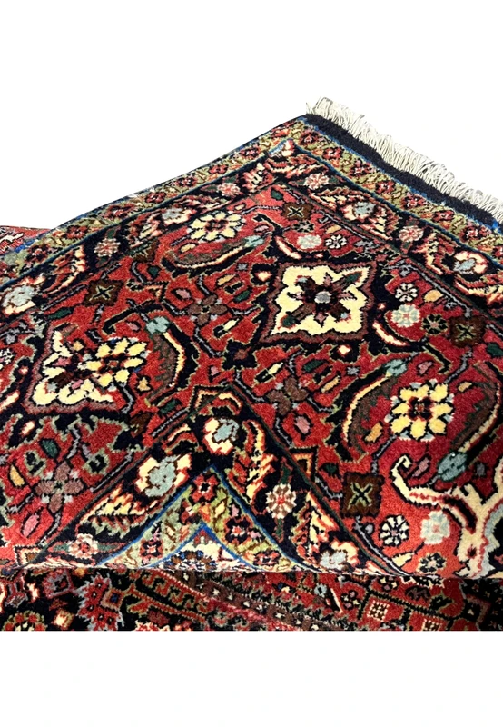 Folded view showing the dense wool pile, the precision of the design, and the structural weight characteristic of Persian iron rugs
