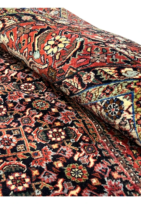 Macro detail of the central red medallion infill showing flower heads, vine work, and the depth of the wool pile from above