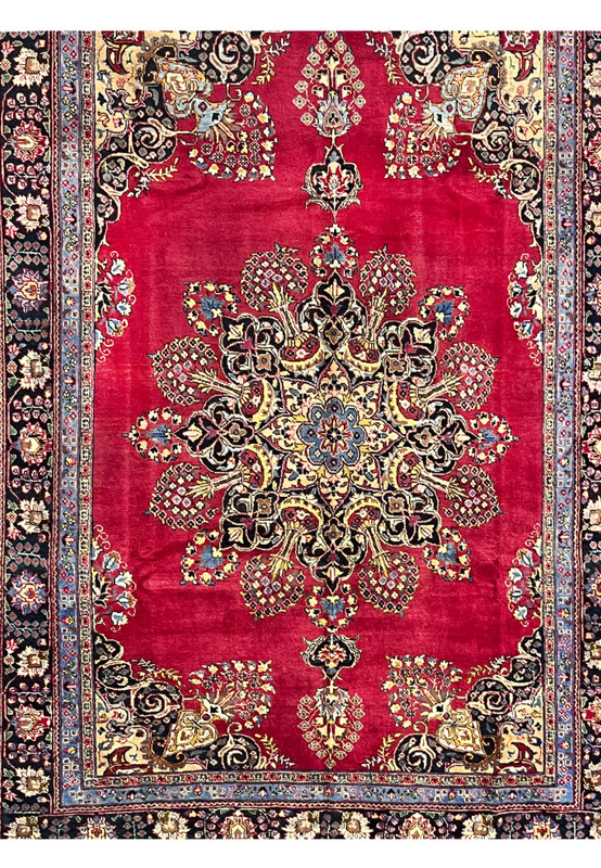 Closeup of Persian Kerman midfield showing the lobed sunburst medallion radiating into bouquet sprays on deep red ground