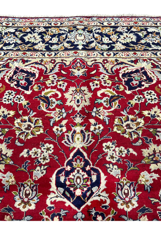 Upper field section of Persian Isfahan rug featuring upper pendant cartouche meeting top border with dense crimson floral allover