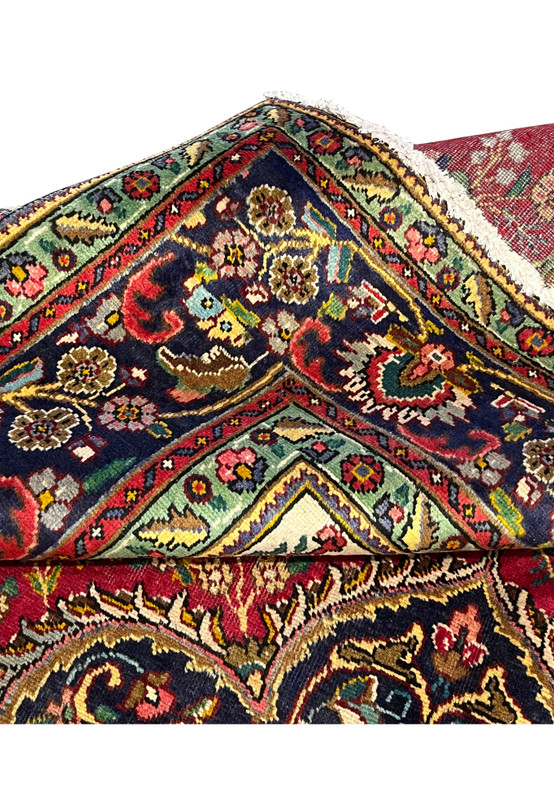 Folded edge of Persian Kerman rug with backside detail showing fine 200 KPSI knotting, cotton foundation, and tight bound selvage
