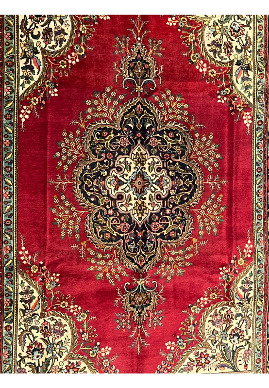 Closeup of Persian Kerman midfield showing layered cartouche medallion with navy lobes and ivory inner reserve on deep red ground
