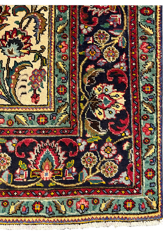 Wide border closeup of Persian Kerman rug featuring scrolling palmettes, red rosettes, and turquoise outer guard stripe on dark navy ground