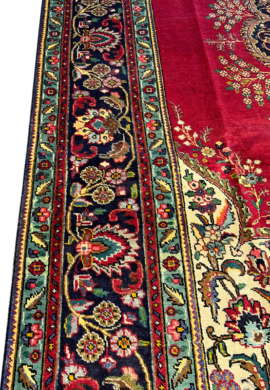 Detailed border closeup of authentic Persian Kerman rug featuring dense palmette repeats, rose florals, and ivory leafwork on navy ground
