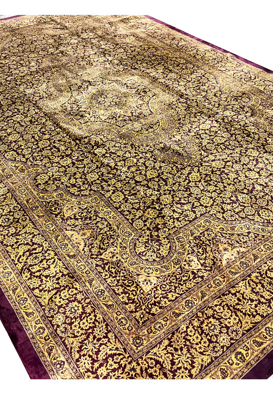 Angled studio view of signed Naimi Qum pure silk rug highlighting the directional silk sheen across the gold floral field