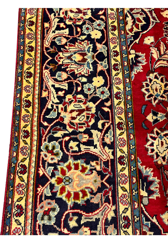 Border closeup of Persian Najafabad rug, ivory and gold palmette vines on deep navy ground with sky blue floral accents