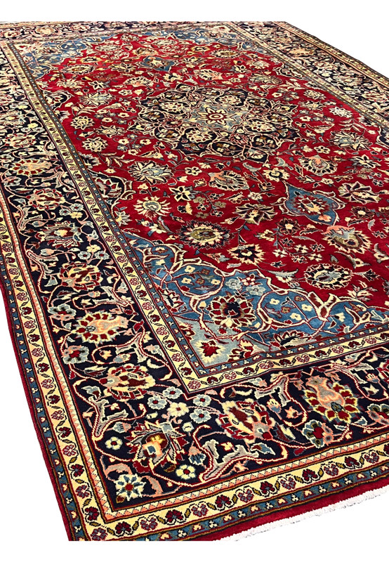 Angled studio view of 8x13 Persian Najafabad rug, rose red field and navy border holding the diamond medallion in perspective