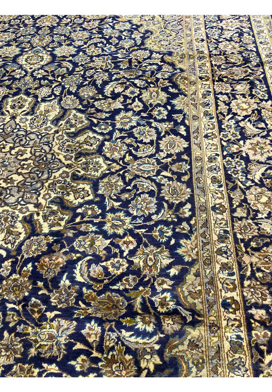 Color close-up of Persian Kashan field, deep navy ground with ivory cream camel and olive green floral work, hand-knotted
