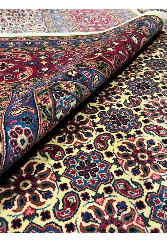 Rolled corner of fine Persian Mashad rug, Kork wool pile visible, ivory field and red border, 400 KPSI hand-knotted