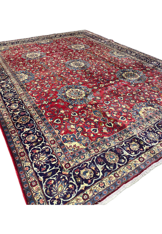 Angled view of oversize 10x13 Persian Isfahan rug, navy border and red field with allover floral, fine wool on cotton for formal living room
