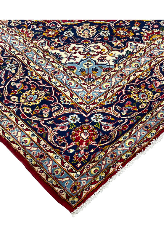 Corner edge of 10x15 Persian Kashan rug, navy spandrel and crisp guard borders on red field, never used handmade wool