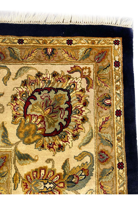 Corner detail of oversize Oriental Jaipur rug, ivory cream fringe meeting midnight blue field with gold border