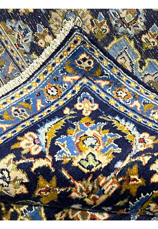 Folded edge of authentic hand-knotted Kashan rug revealing the cotton foundation and navy selvage