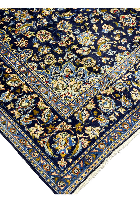 Edge and border corner of hand-knotted wool Kashan rug with ivory and gold floral detail on navy
