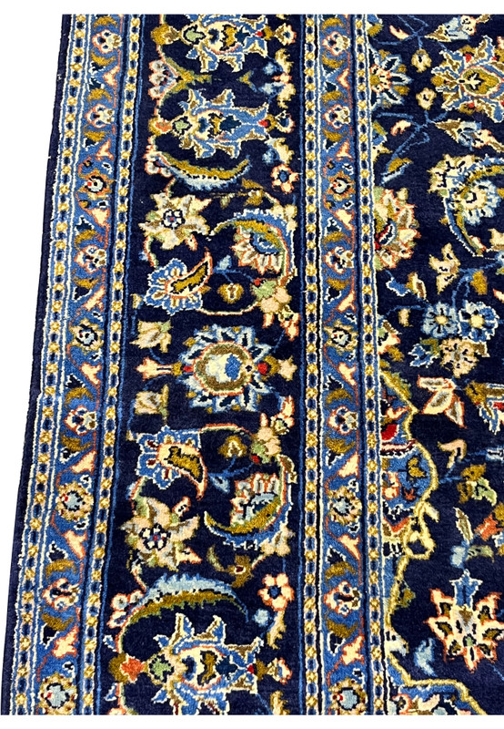Border closeup of Persian Kashan rug showing finely drawn palmettes and sky-blue guard band florals